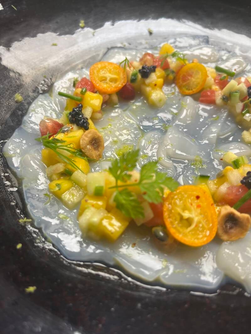 Luxury raw scallop carpaccio adorned with mango, passion fruit, fresh caviar, and green apple, high-end private chef signature starter.
