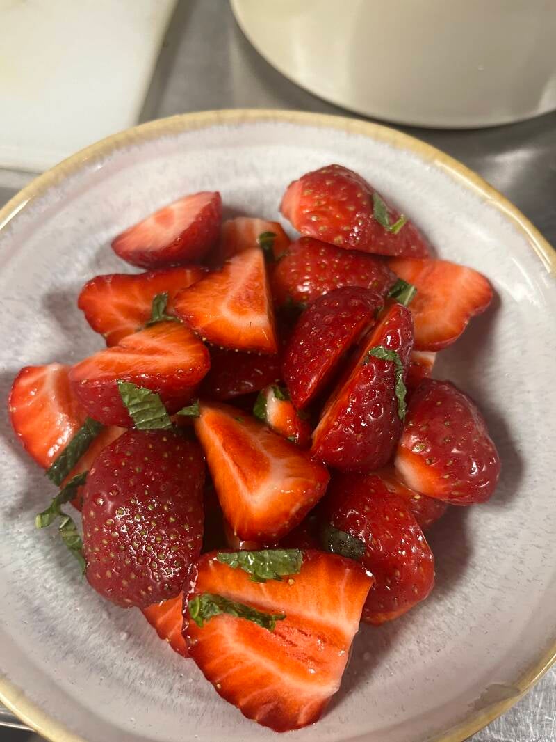 Fresh gourmet strawberries with mint leaves in a ceramic bowl, elegant yacht catering dessert.
