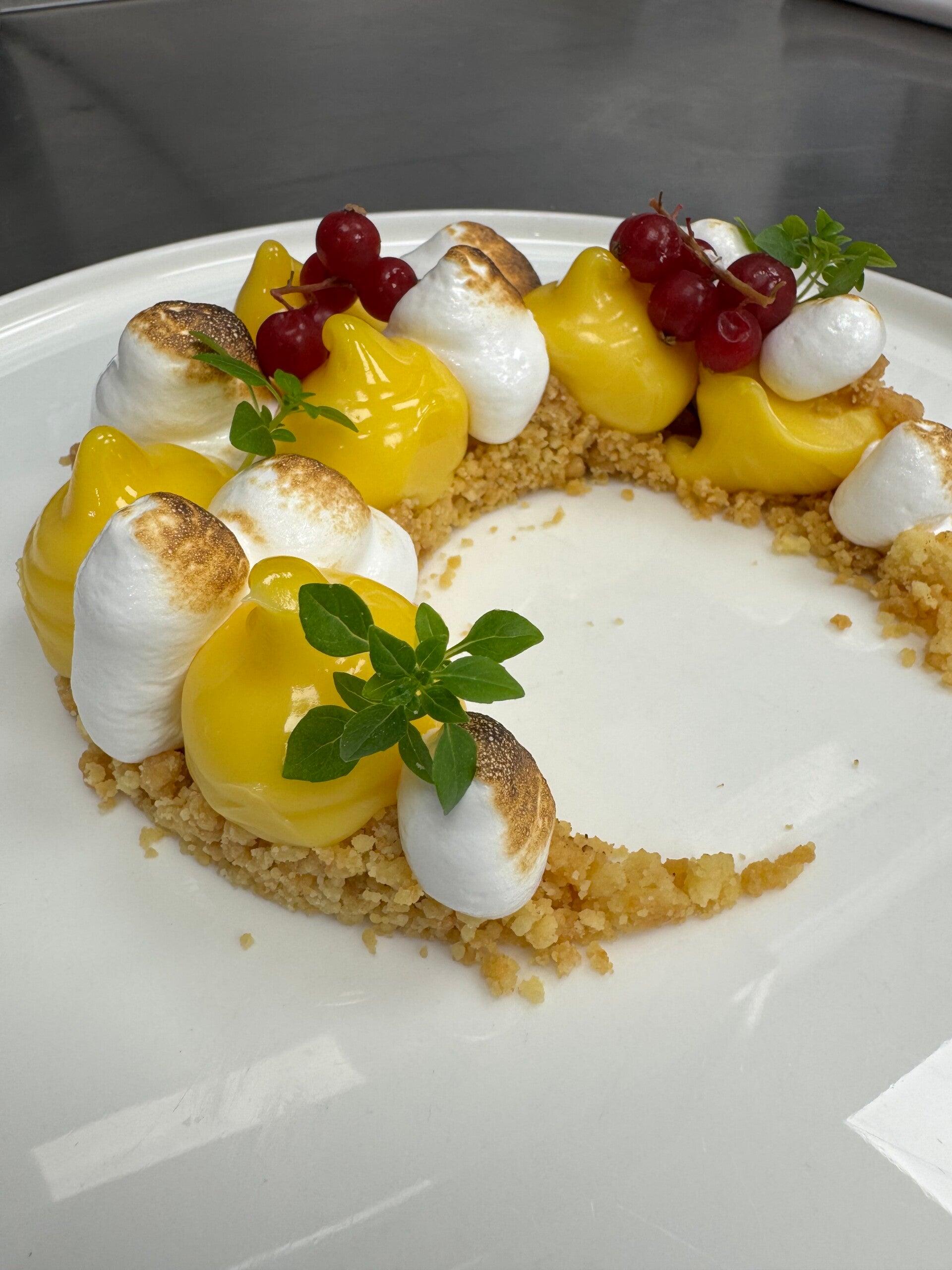 Deconstructed lemon meringue tart with citrus cream and golden crumble, refined French-style dessert.