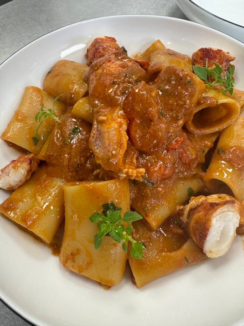 Artisanal paccheri pasta with fresh lobster sauce and aromatic herbs, fine dining yacht catering.