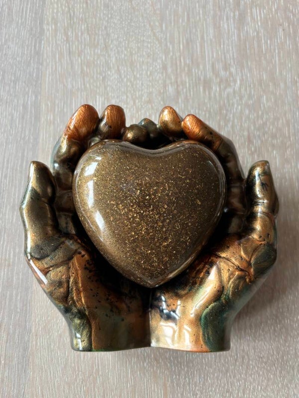 Handenschaal in een mix van kleuren (brons zwart groen goud) gecombineerd met een as-urn hart in brons