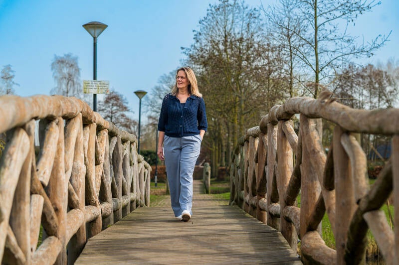 Judy Kamsteeg loopt over een brede brug die symbool staat voor de ruimte die ontstaat bij loopbaanontwikkeling.