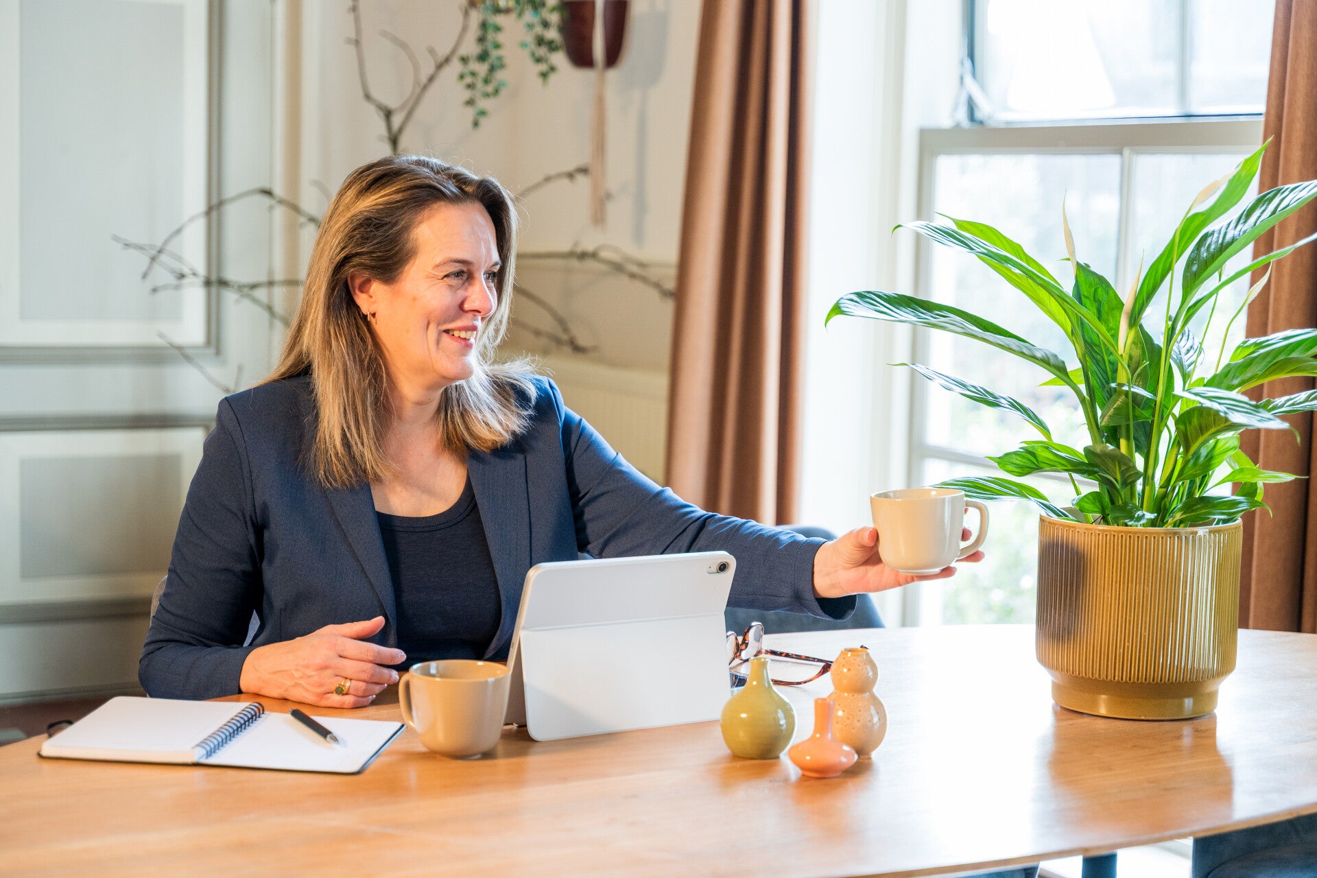 Loopbaancoach Judy Kamsteeg reikt lachend een kop koffie aan voor een positieve wending in je loopbaan.