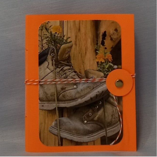 Mini Junk Journal. Orange with an old pair of work boots hanging the flowers growing in them.