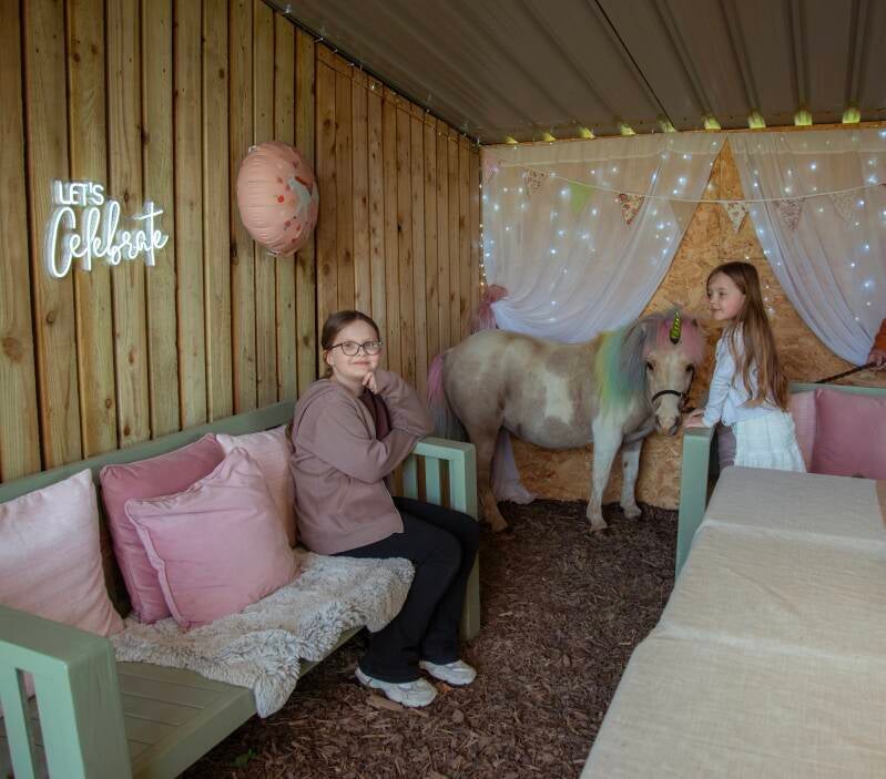 Children sat next to unicorn pony 