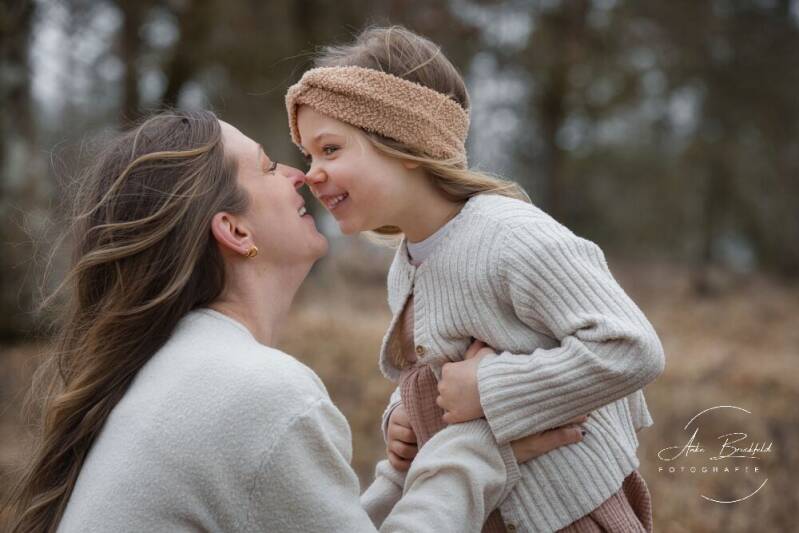 Mutter und kleine Tochter geben sich einen Nasenkuss.