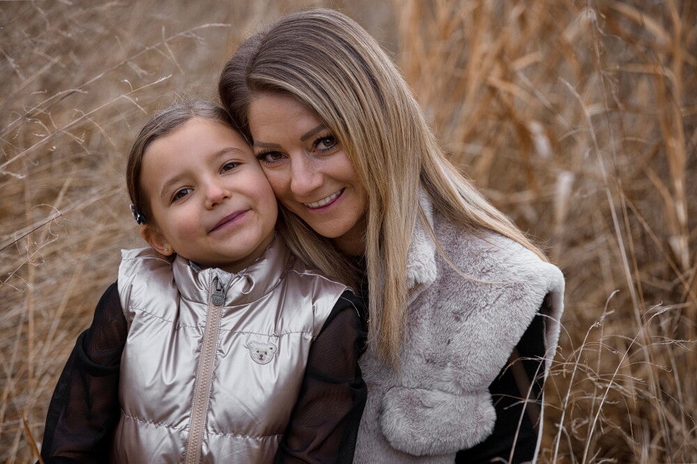 Mutter und Tochter sitzen in hohem Gras.
