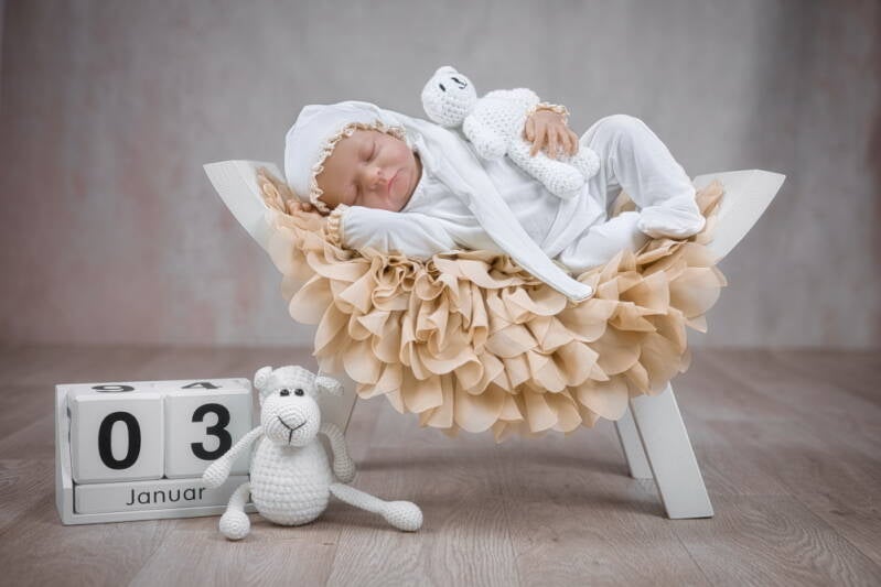 Neugeborenes schläft auf weißem Schemel.