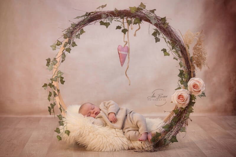 Neugeborenes schläft in einem blumengeschmückten Reif. 