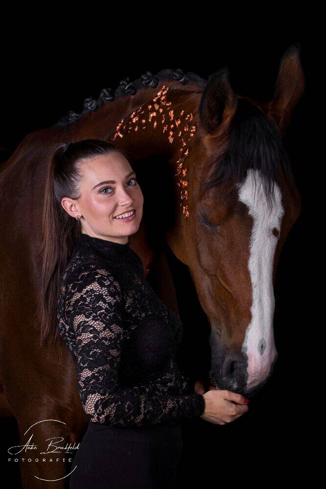Junge Frau mit Pferd im Portrait vor schwarzem Hintergrund.