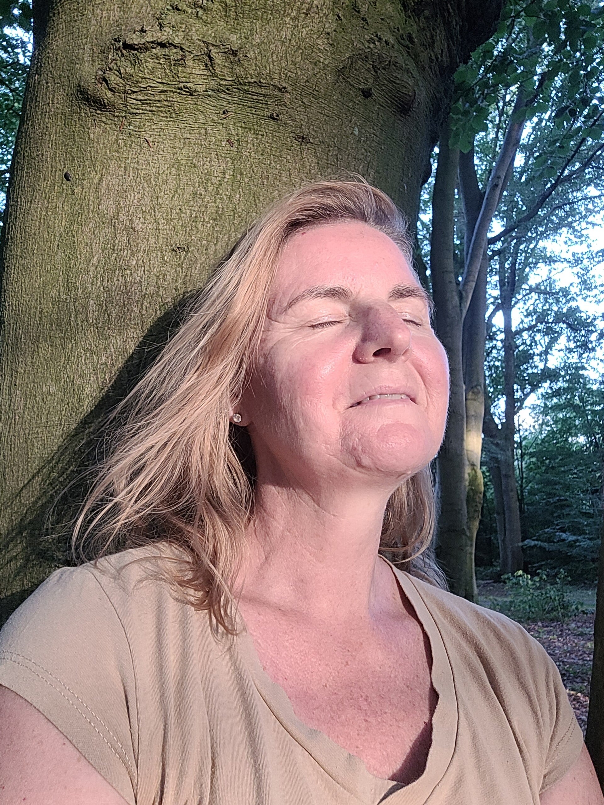 Mary Stroet ontspannen tegen een boom leunend in de natuur - Van Weten naar Voelen.