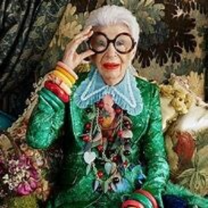 Kleurrijke vrouw: Iris Apfel met armbanden en kettingen en haar grote ronde statement bril