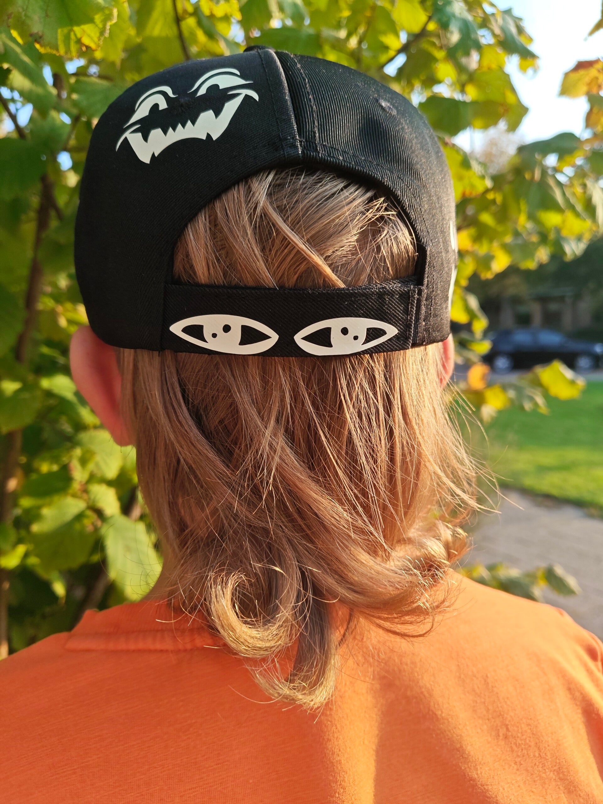 Fright Bite cap, bij daglicht. Deze licht op in de avond als het donker wordt. Achterop ook oogjes die je eventuele volgers meteen afschrikken!