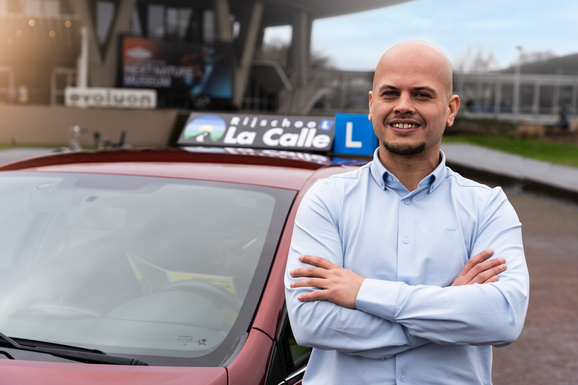 Our experienced driving coach in Eindhoven standing next to a training car, specialized in personal driving guidance.