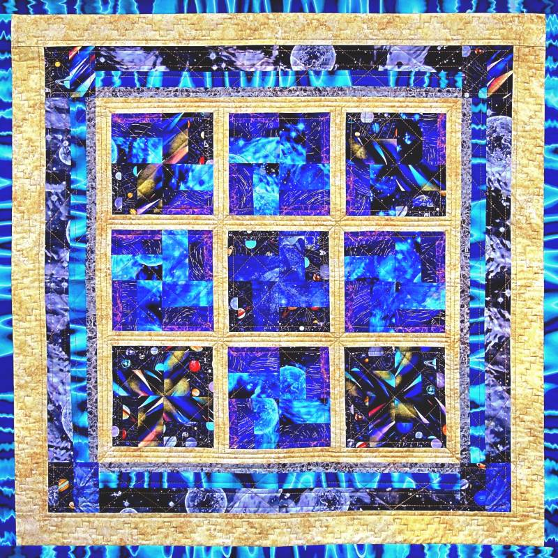 Onze eerste quilt: Q1: Genesis. De oerknal in beeld  gebracht met achter een raam een explosie van kleur. Met rand van planeten en  poollicht.