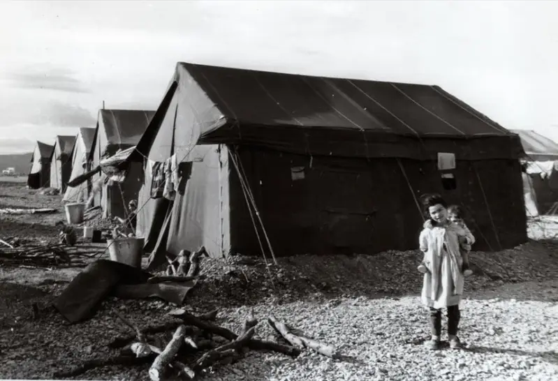 Une fille harkie devant une tente militaire dans le camp en 1962 