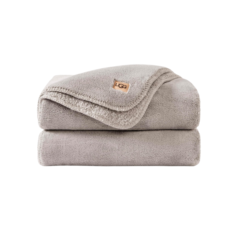 A plush grey throw blanket draped over a couch, inviting rest and comfort in a calm living space.