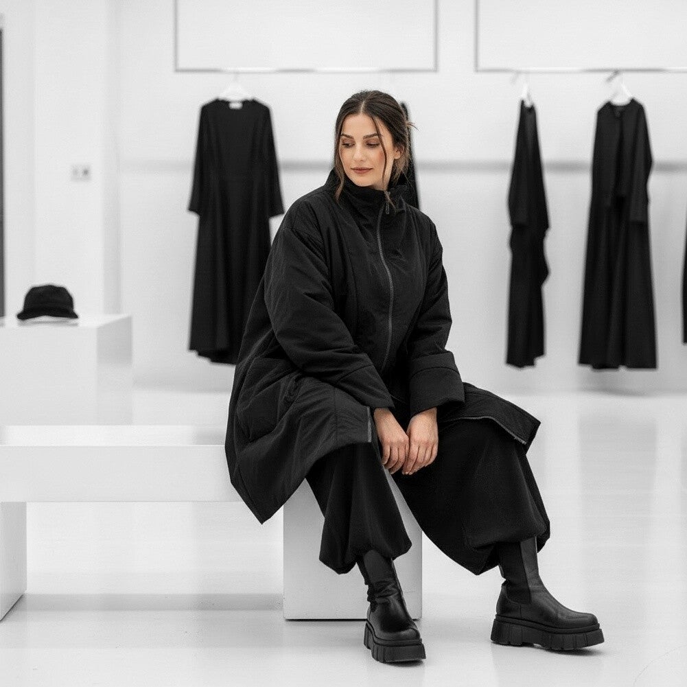 Eine modische Frau steht in einer exklusiven Boutique und probiert einen orangefarbenen Mantel an. 