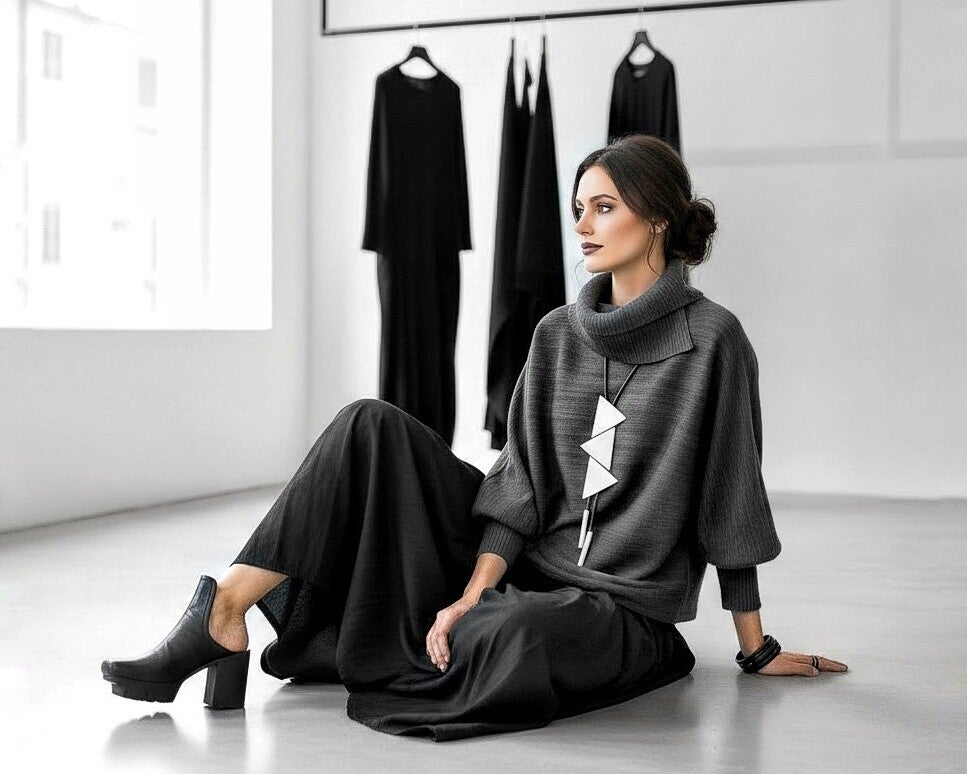 Eine extravagant gekleidete Frau sitzt lächelnd auf einem Hocker in einer Modeboutique 