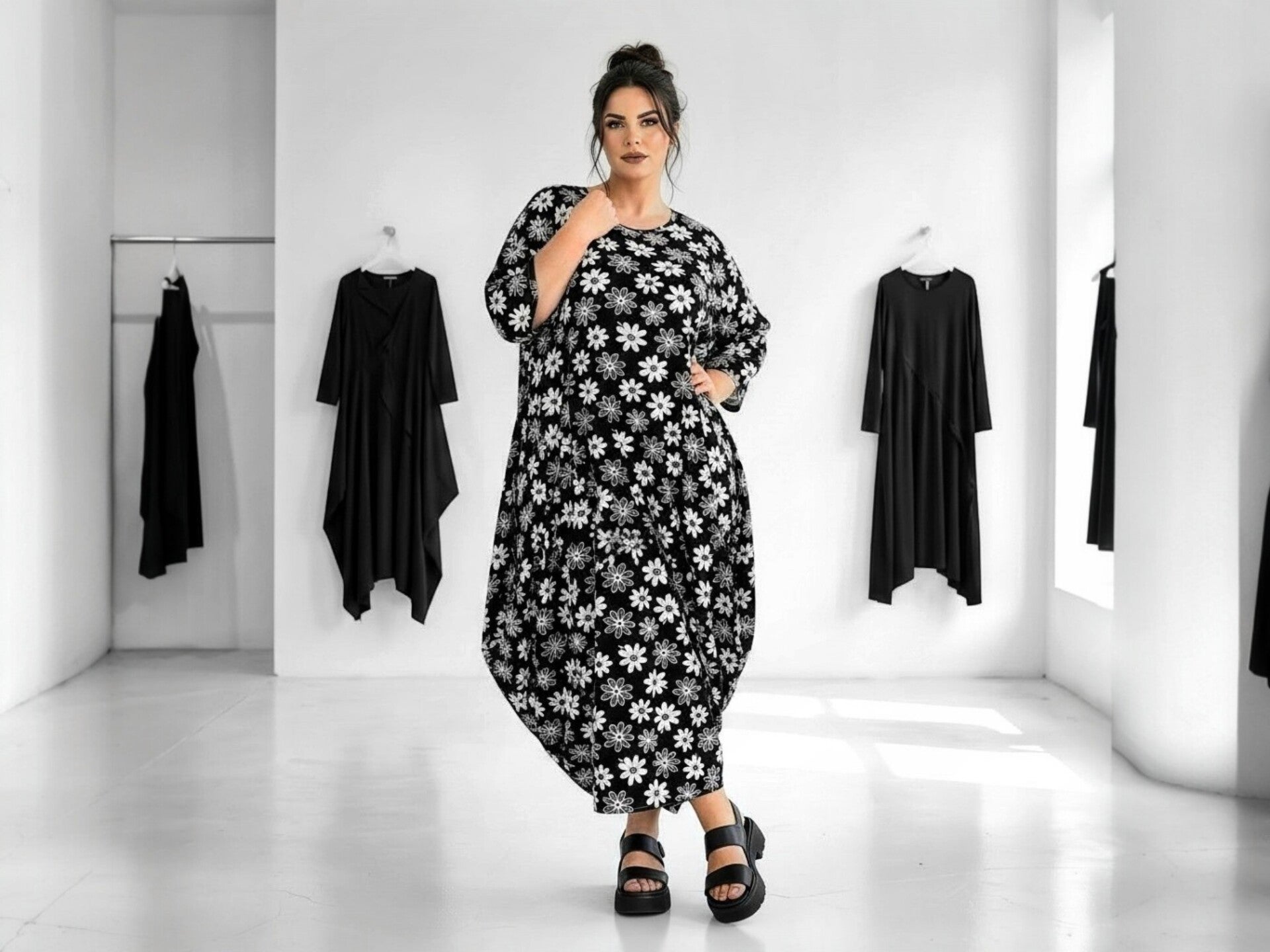 Eine attraktive Frau mit Plus-Size trägt ein schwarz weißes Sommerkleid. Die Frau steht in selbstbewusster Pose in einer  Boutique 
