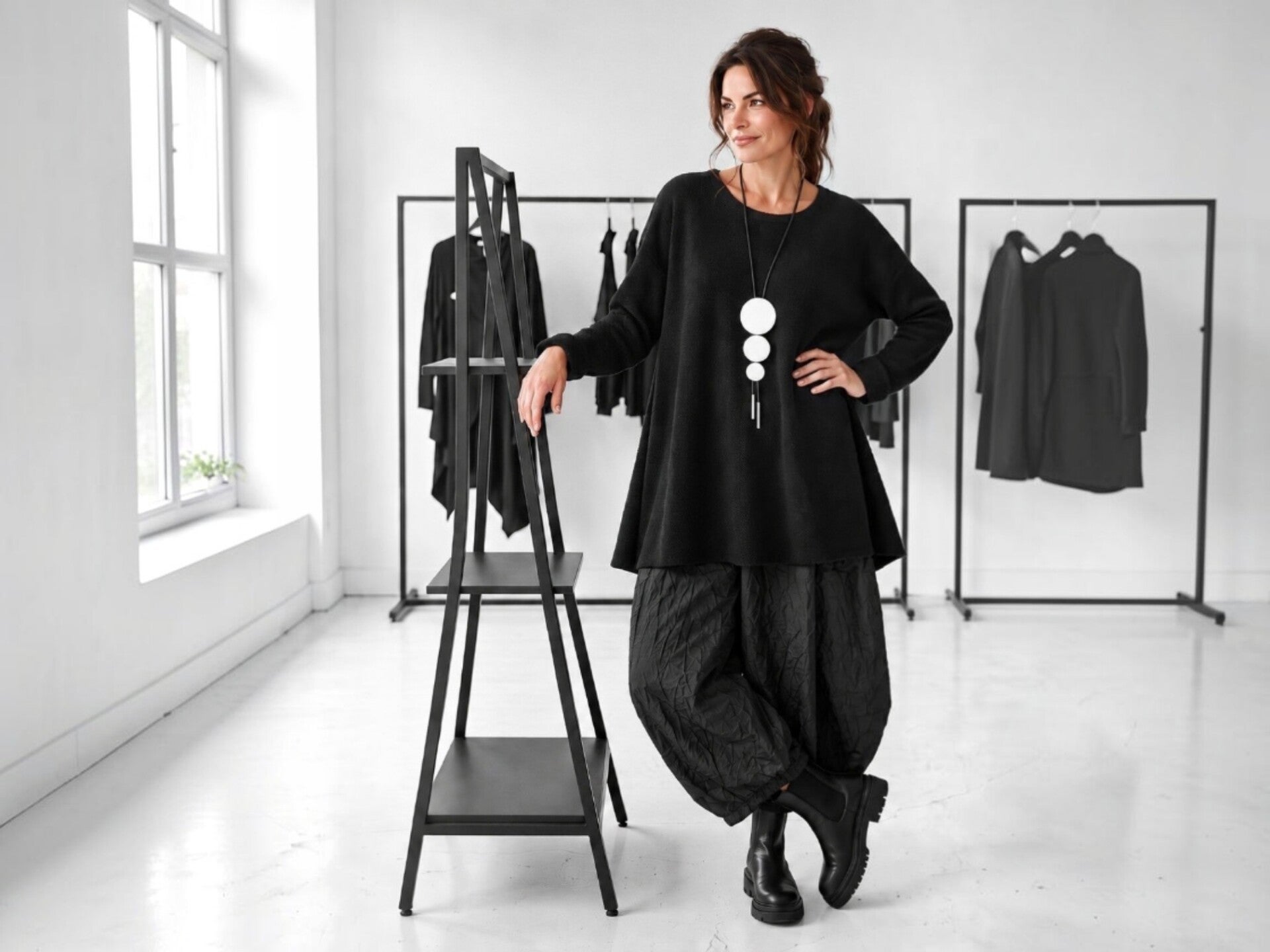 Ein Model präsentiert ein extravagantes Sommer Outfit bestehend aus einer weiten anthrazitfarbenden Ballon-Hose in Kombination mit einem lässigen weißen Obertel mit dunkelgraunen großen Punkten, außerdem trägt sie einen großen schwarzen Stroh-Hut