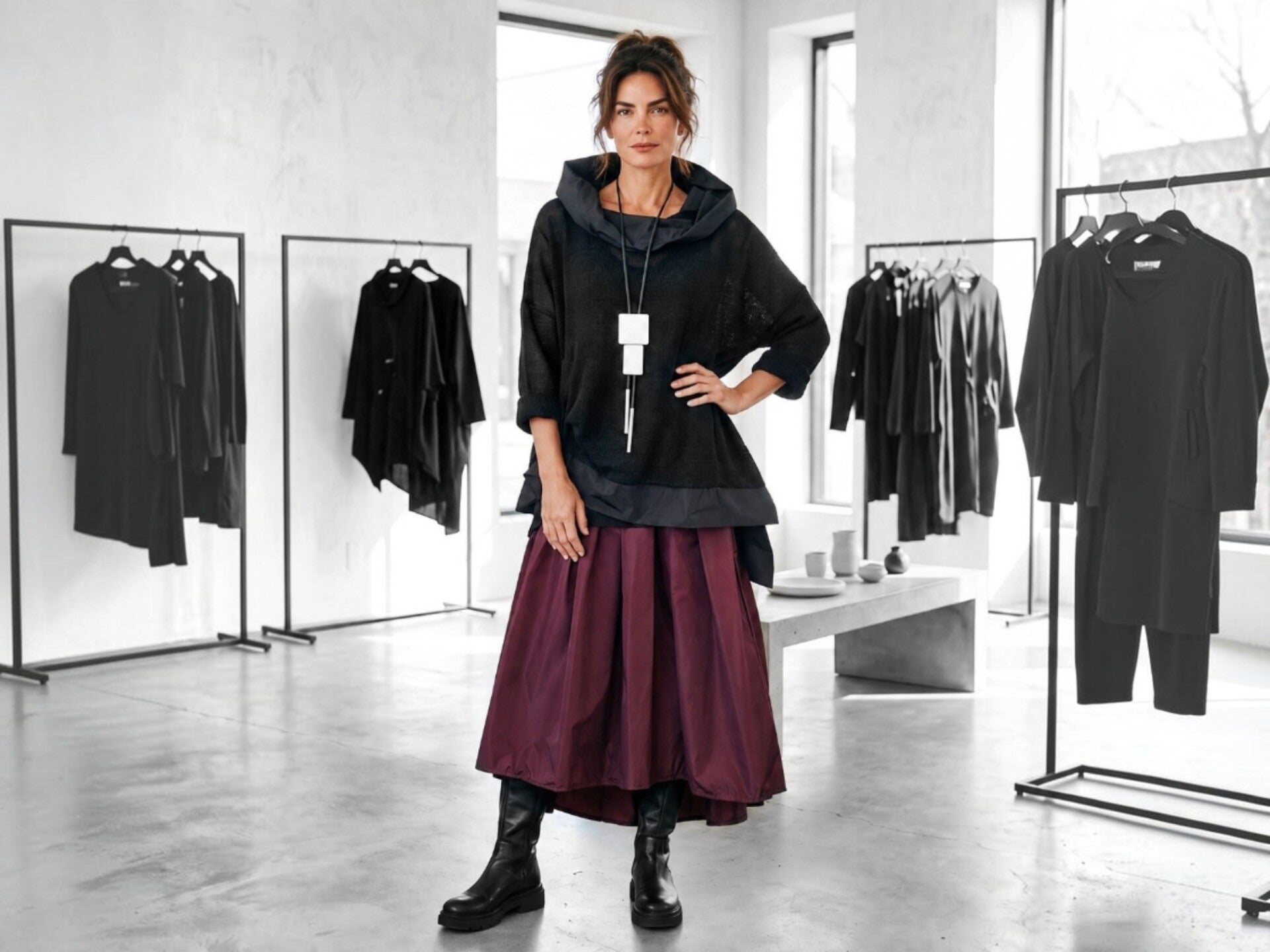 Eine modisch gekleidete junge Frau in einem weiß schwarzem Sommer Outfit steht in einer avangadistischen Modeboutique
