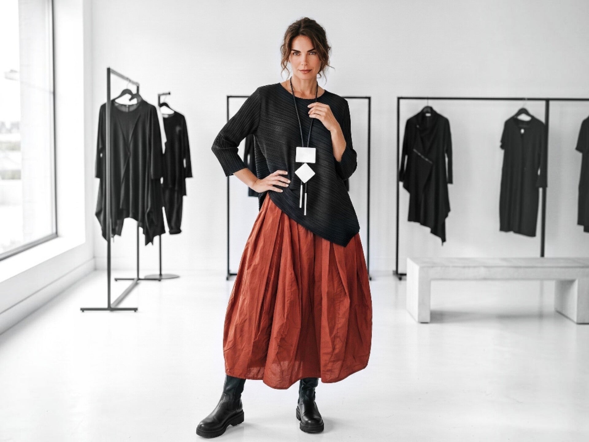 Ein junges Model präsentiert eine modische schwarz-weiße Leinen Kombination, bestehend aus einem langen Zipfel Rock, einem schwarzen Top und einer weißen kurzen Jacke, die schwarz gepaspelt ist