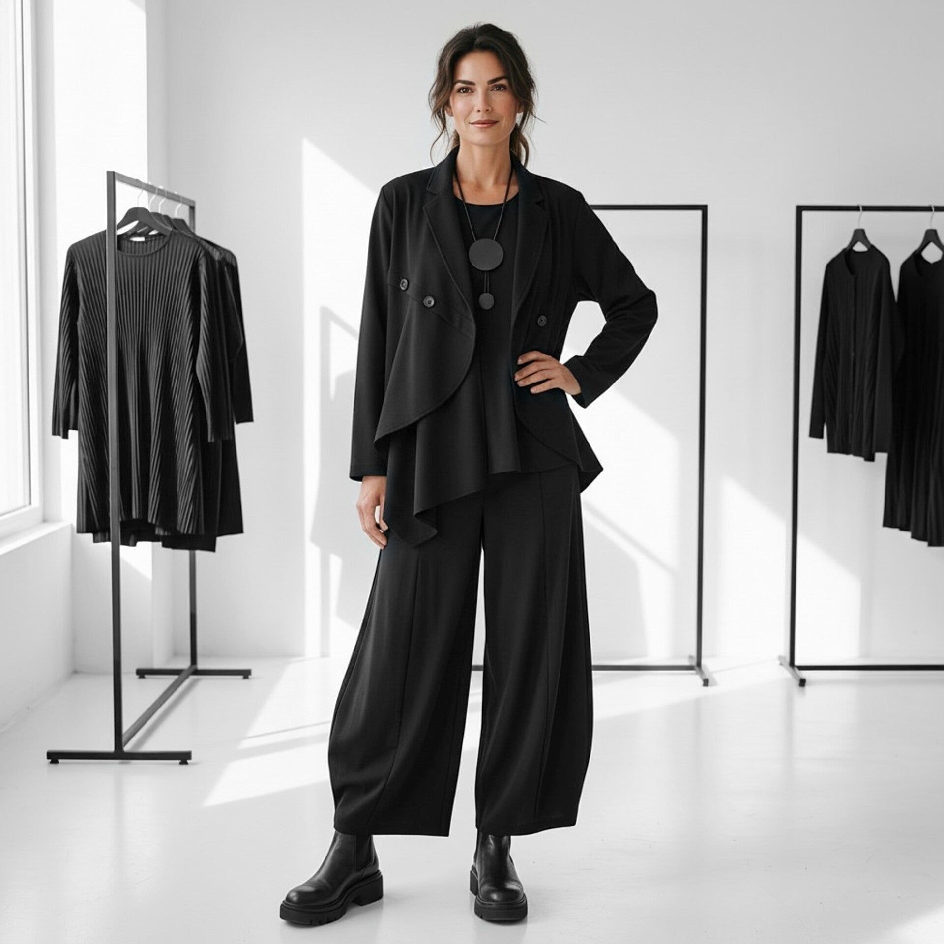 Ein Model trägt ein figurbetonts, langes Abendkleid in schwarz. Das Kleid hat einen effektvollen Kragen und verschiedene Ansätze aus schwarzem Taft M