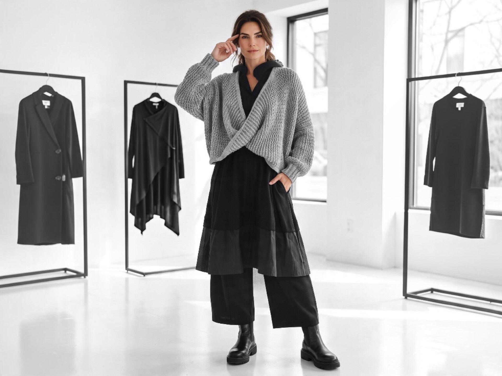 Das Model trägt ein schwarzes, langes  Oberteil mit Taftansatz, dazu eine weit geschnittene, schwarze Hose und dazu einen silbergauen Grob-Strick Pulli im modischen  oversize- Look 