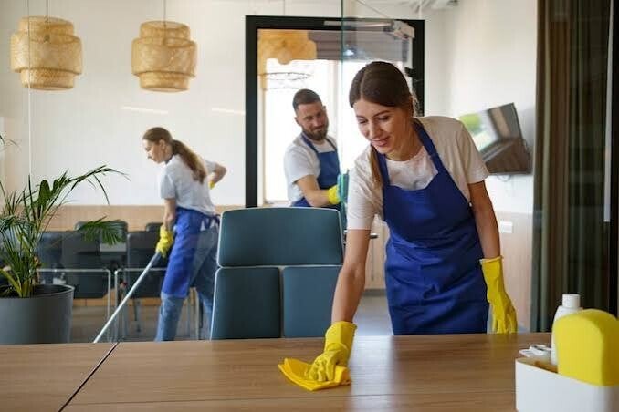 Cleaning team wiping surfaces and vacuuming a modern office, delivering spotless, professional commercial cleaning results.