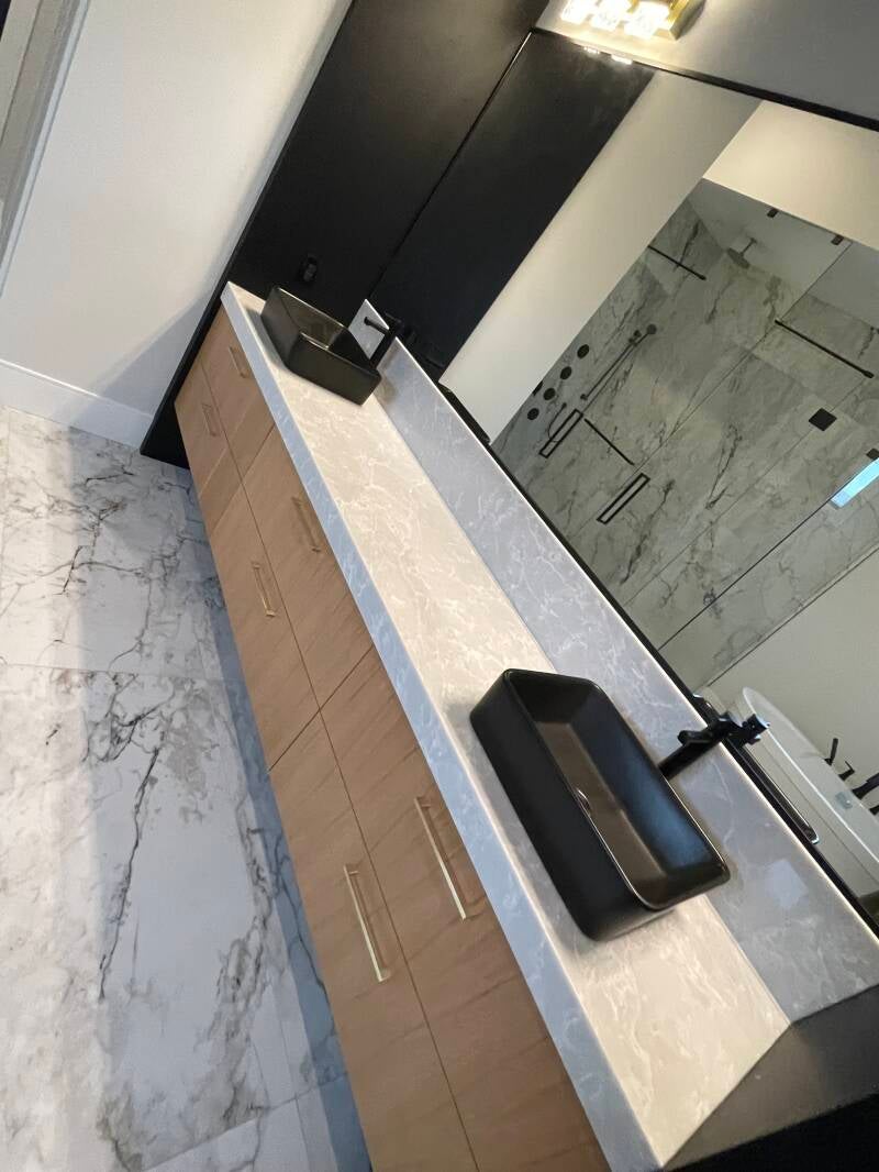Bright modern bathroom with spotless marble floors, clean double‑sink vanity, and a pristine glass shower showcasing professional cleaning quality.