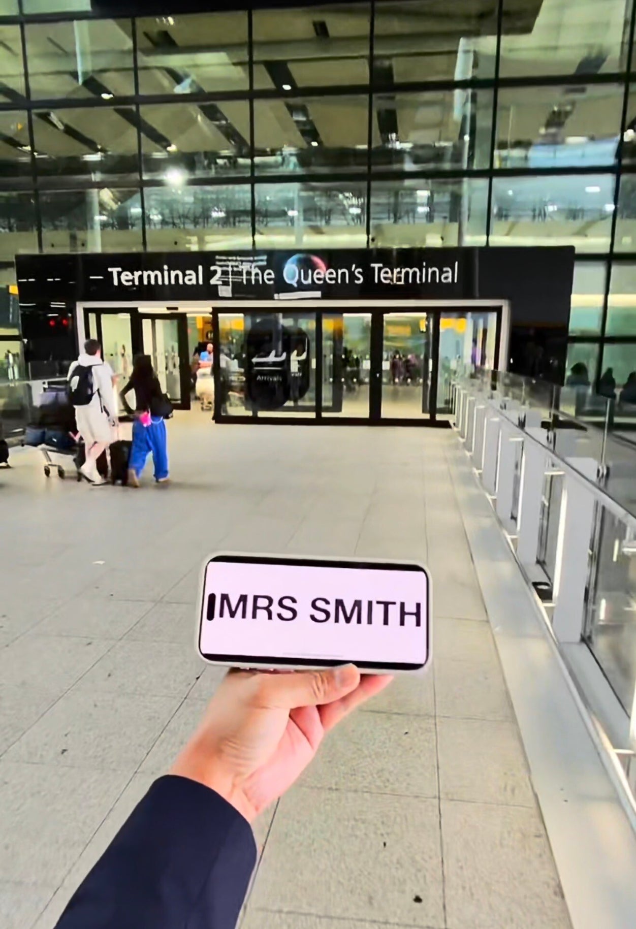 Beyond Elite Travel chauffeur waiting inside Heathrow Terminal 2 arrivals holding a passenger name board