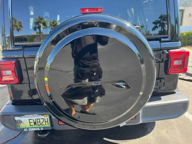 Restored black tire cover with a high-gloss finish and clear reflection after professional paint correction.