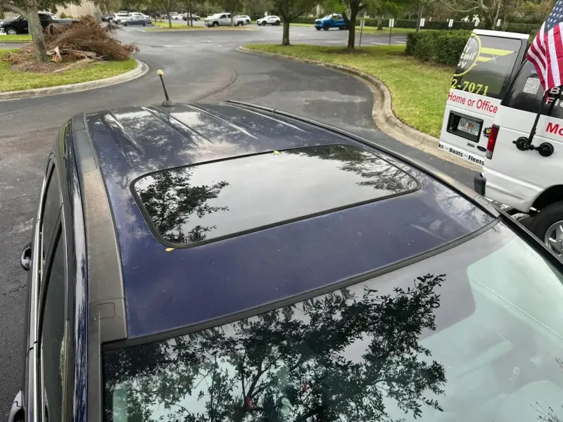 Oxidized and sun-damaged car roof with hazy reflections and worn paint around the sunroof.
