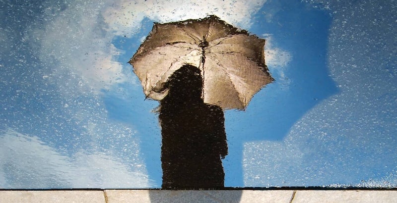 Reflective image of female holding a umbrella
