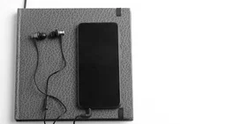 Black phone on grey book with earbuds