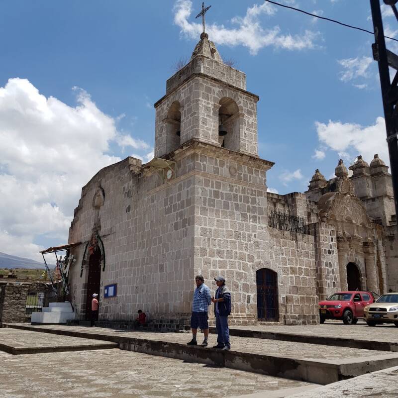 Koloniale kerk met klokkentorens en bergen bij een plaza in Zuid-Peru.