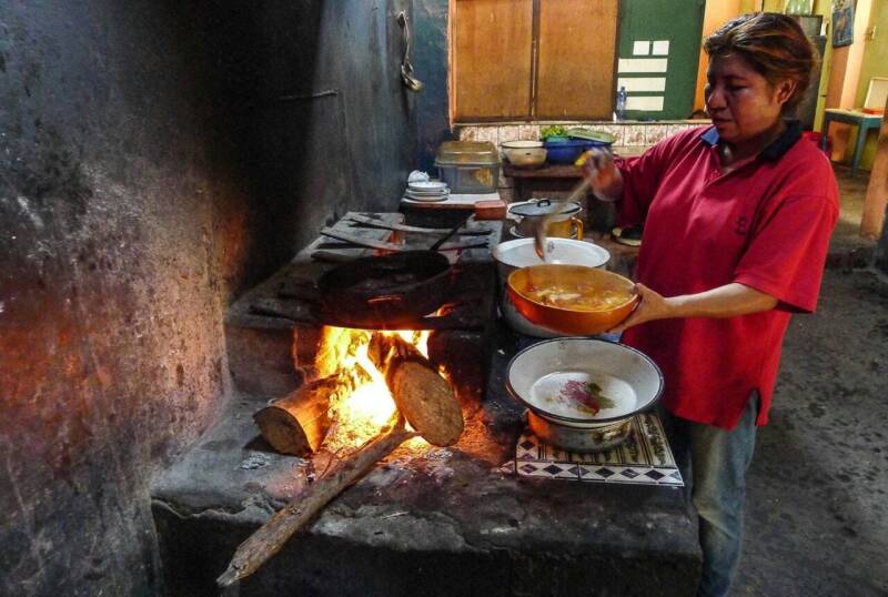 Vrouw bereidt een traditioneel Peruaans gerecht boven een open houtvuur in de keuken van een picantería in Arequipa.
