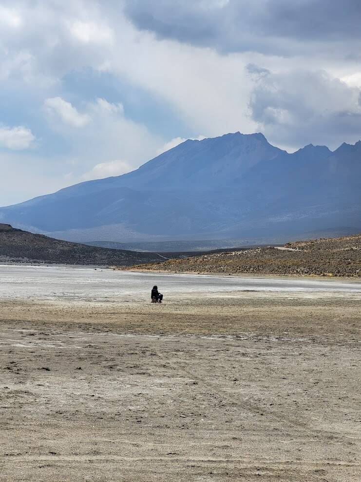 Bezoeker geniet van de stilte op Laguna de Salinas met de vulkanen van Zuid-Peru op de achtergrond.