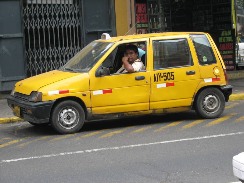 Druk verkeer in Lima met taxi's, bussen en motortaxi's.