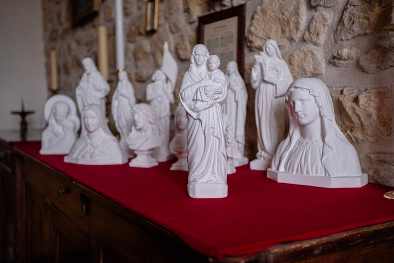 Sculpture religieuse reproduite par l'atelier statuaire parmi les autres statues catholiques de la boutique.