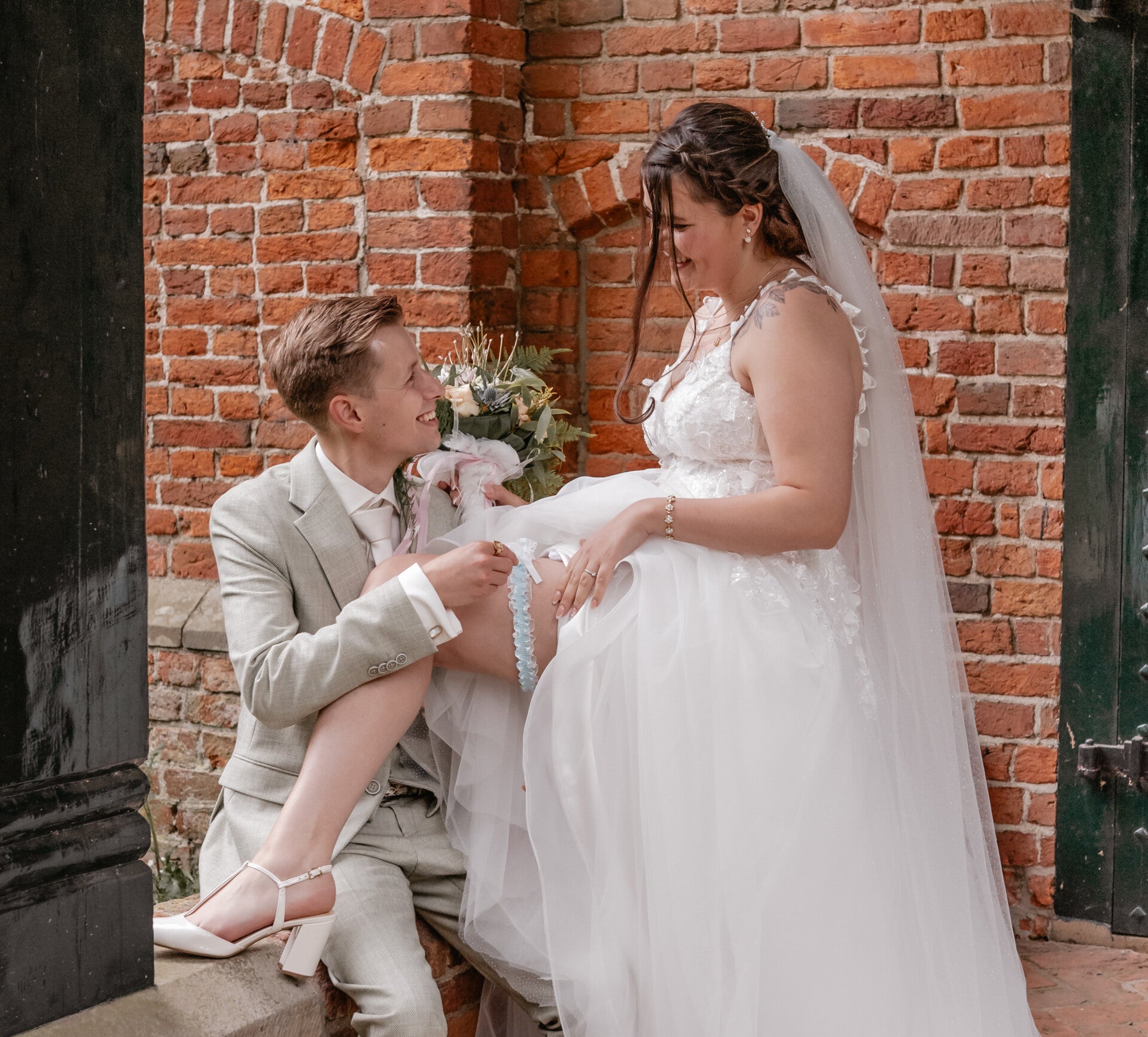 bruidsboeket op de voorgrond met het bruidspaar daarachter in Appingedam