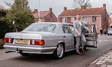 de bruidegom stapt uit zijn prachtige trouwauto om zijn bruid op te halen voor de grote dag