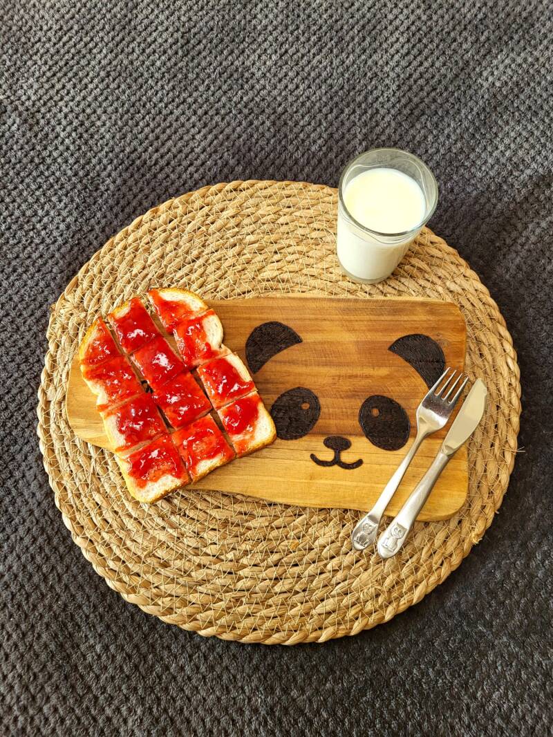 Broodplankje met broodje jam en glas melk
