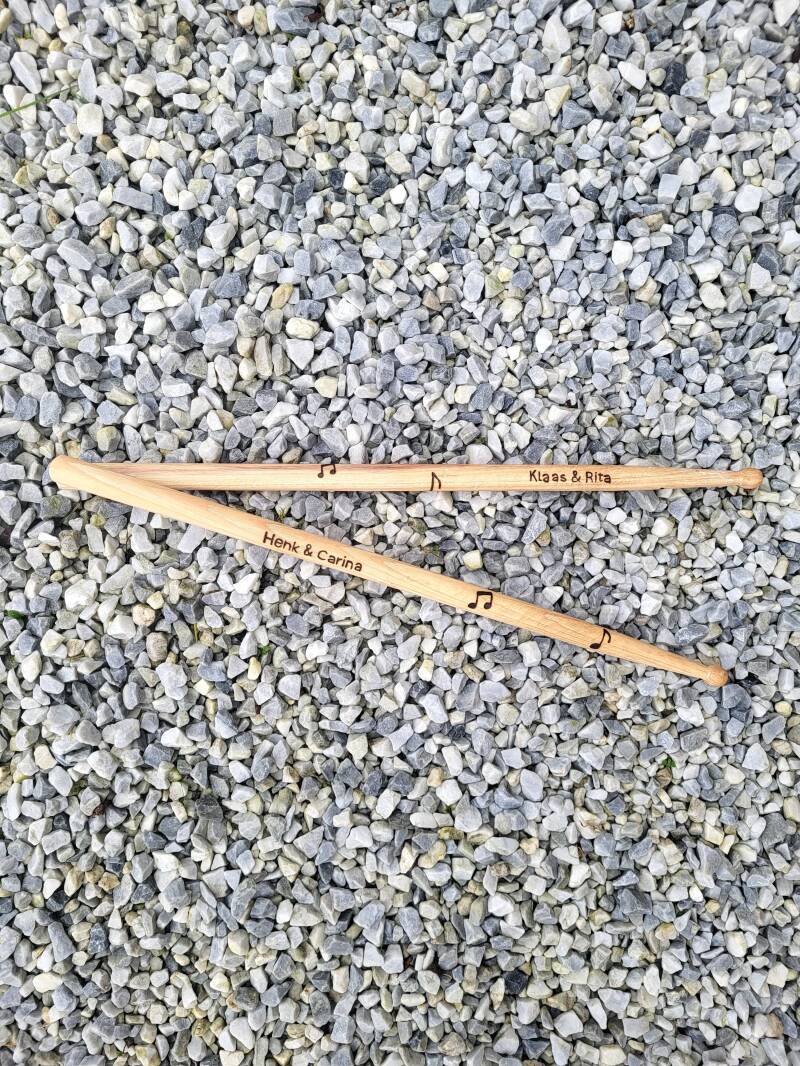 Drumstokken met namen van geliefde houtgebrand voor in een rouwboeket.