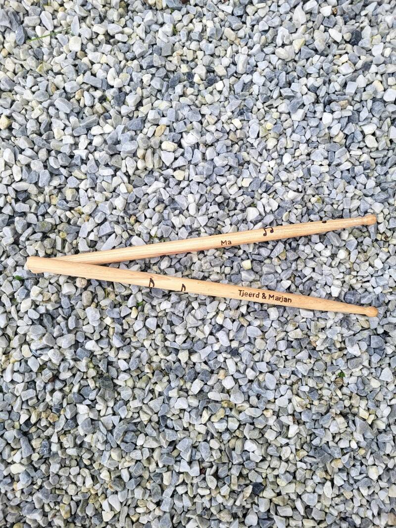 Drumstokken met namen van geliefde houtgebrand voor in een rouwboeket.