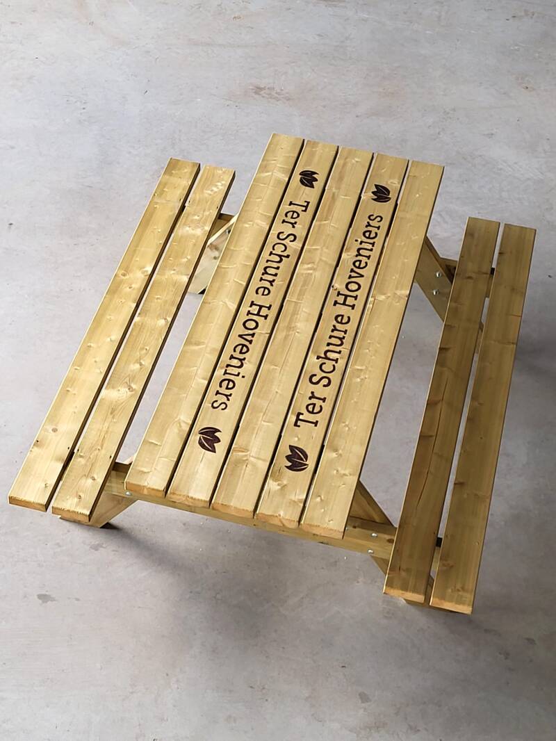 Picknicktafel met twee keer het logo van Ter Schure Hoveniers erop houtgebrand