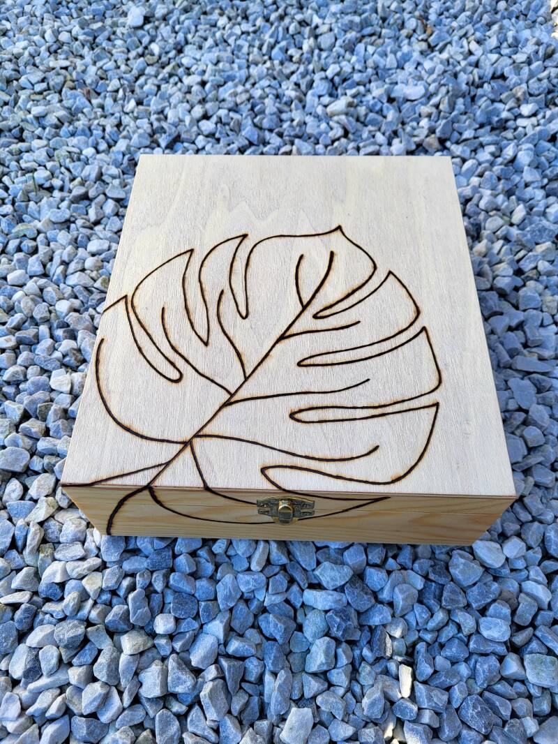 9 vakken theedoos houtgebrand met een palm blad erop. 