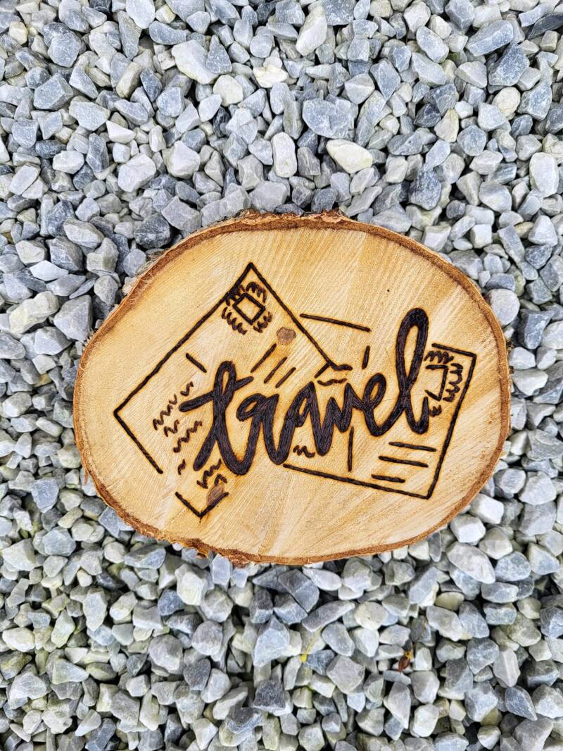 Boomschijf met de tekst Travel en ansichtkaarten erop houtgebrand