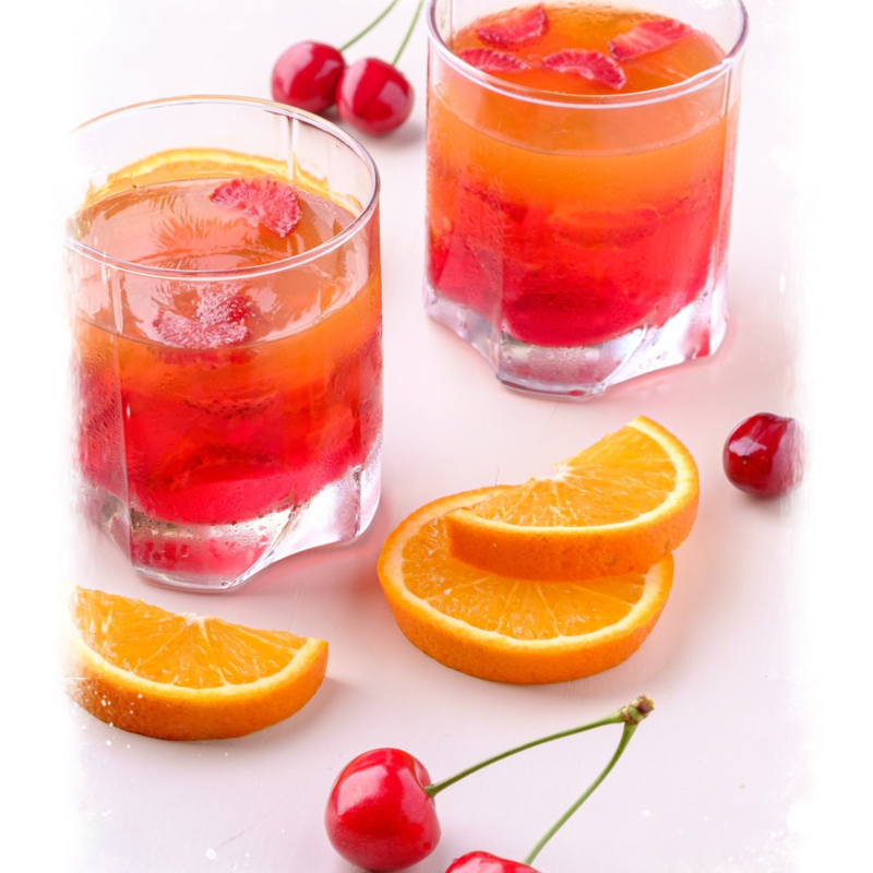 Glazen met Bolero siroop, schijfjes sinaasappel en kersen.